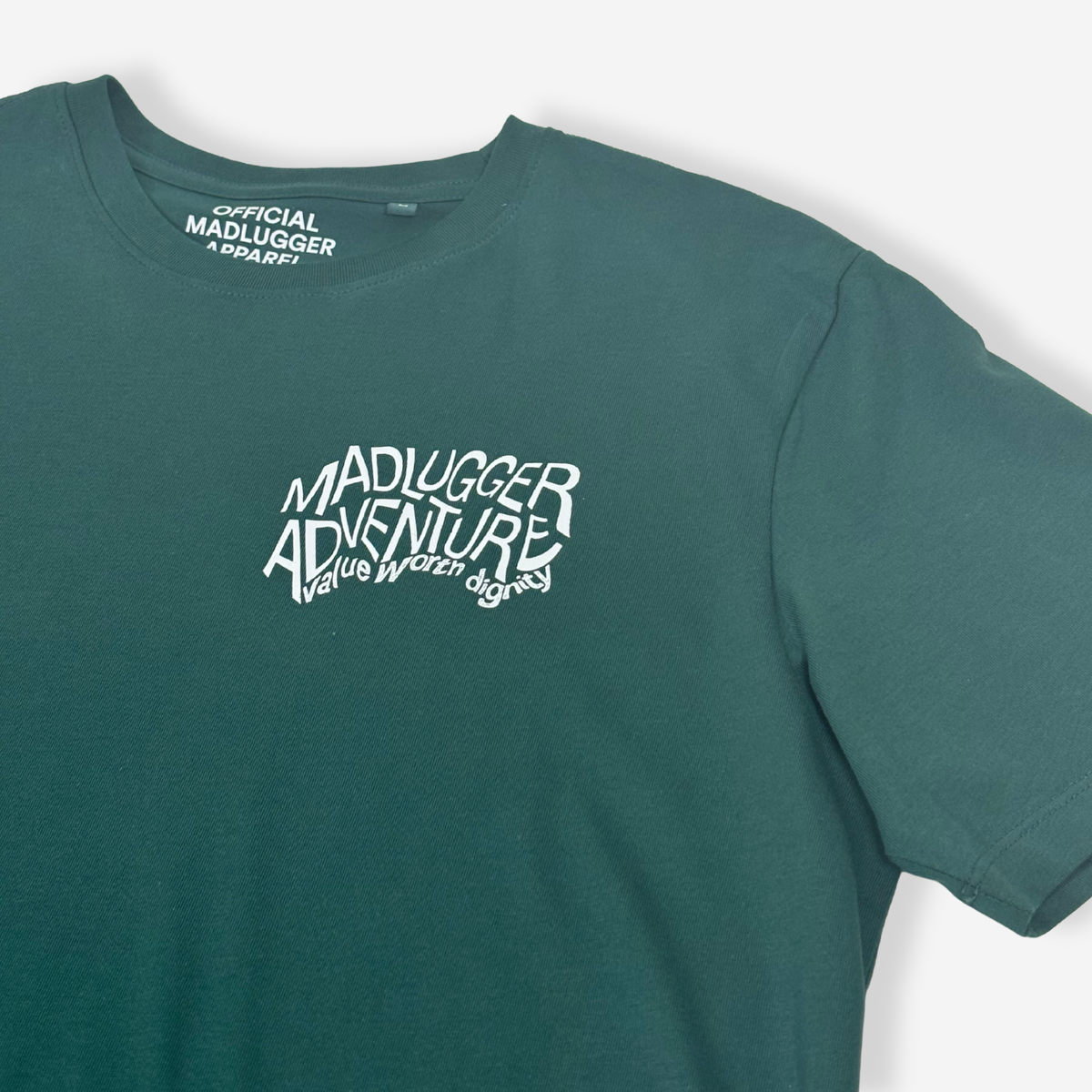 A pine green crewneck t-shirt with a stylised white graphic on the chest reading 'MADLUGGER ADVENTURE and 'OFFICIAL MADLUGGER APPAREL' printed inside the collar, shown against a light gray background.