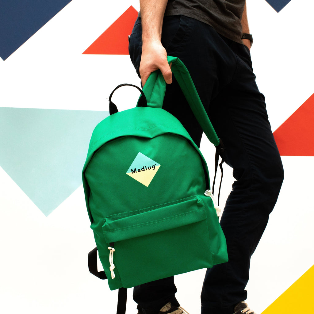 Madlug Classic Backpack in Green. Model holding by strap.