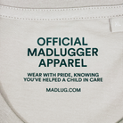 Close-up of a stone colour t-shirt neck label with black printed text reading 'OFFICIAL MADLUGGER APPAREL' and 'WEAR WITH PRIDE, KNOWING YOU'VE HELPED A CHILD IN CARE' along with 'MADLUG.COM' 